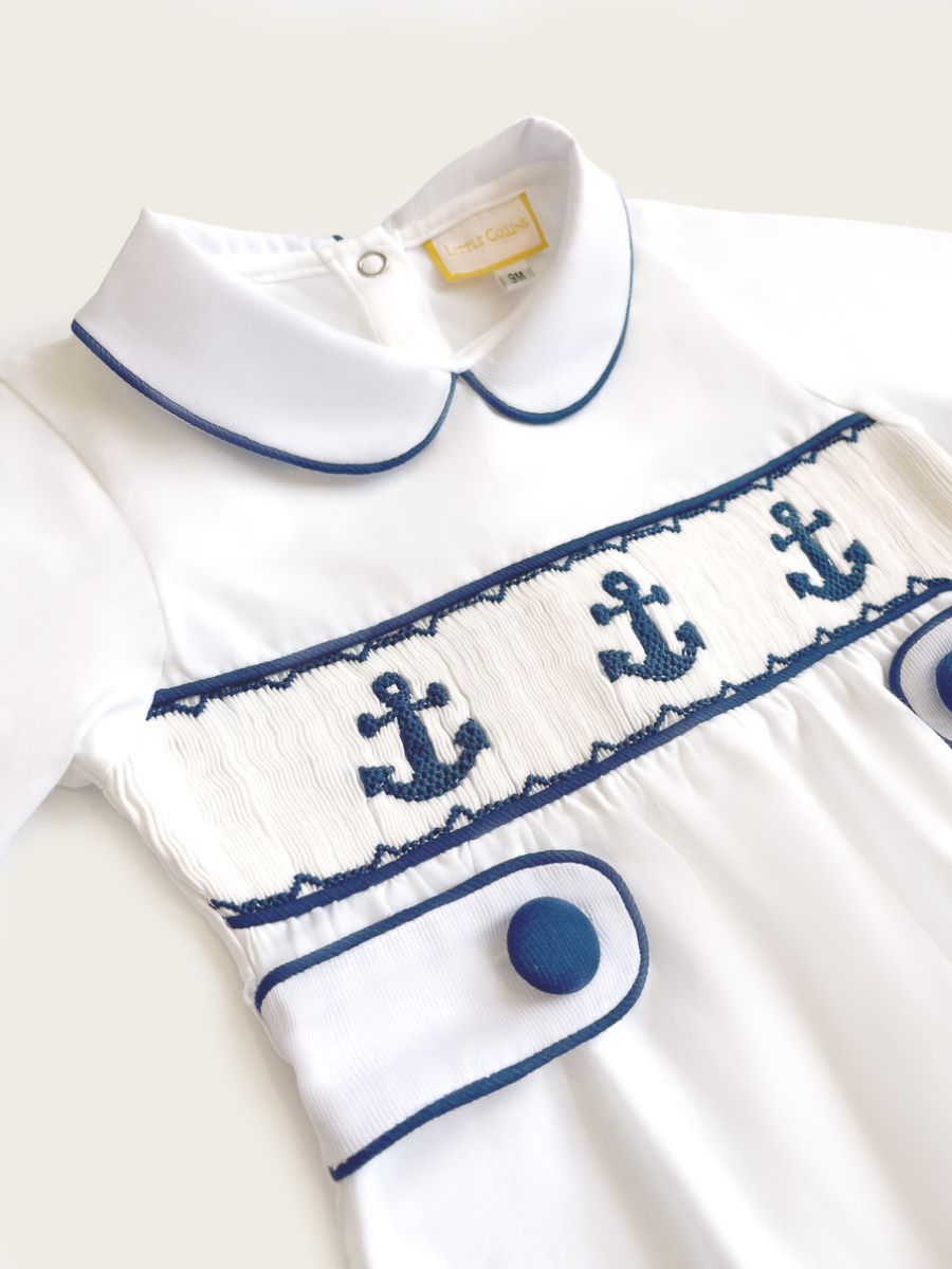 Little Collins Clothing white babygrow with smocking, peter pan collar and blue anchors front far view
