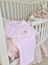 Pink and white striped long sleeve pyjamas with a ballerina embroidered onto the front pocket folded neatly on a child's cot ready for bed time.