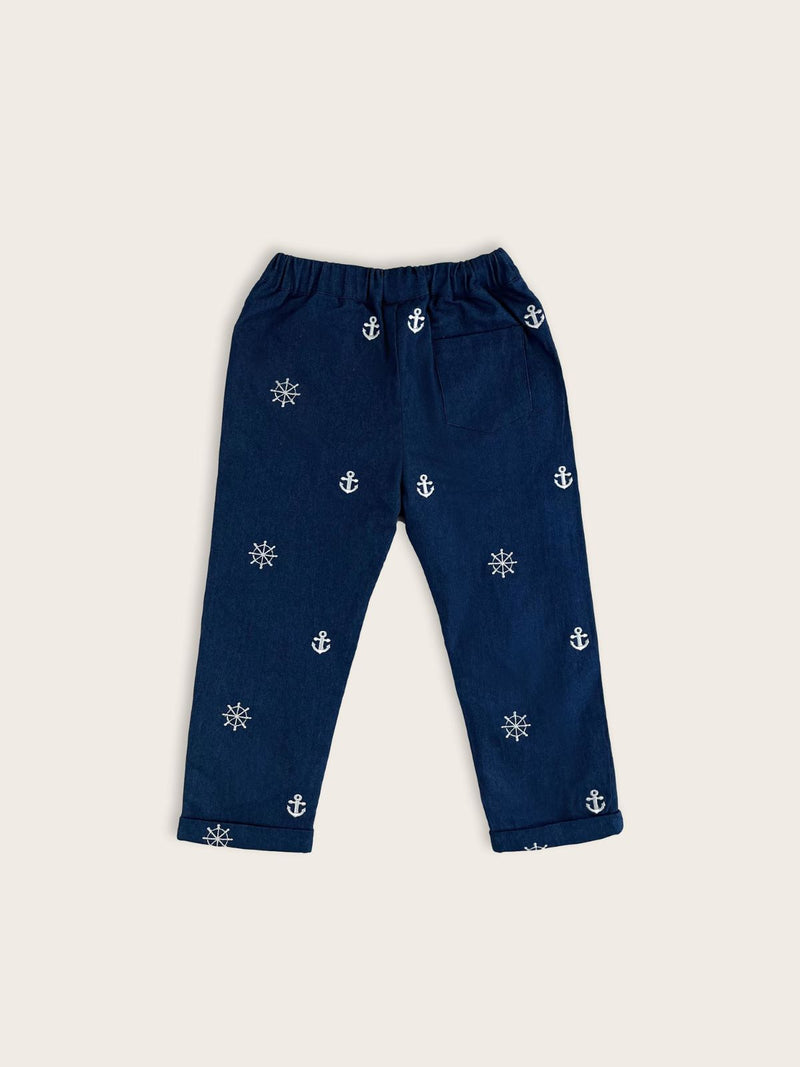 Boys trousers in a blue denim with white nautical anchors and ship's wheels motifs rear view with back pocket detailing.